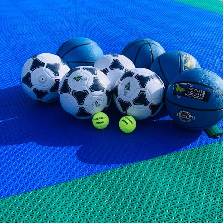 Various sport balls on modular sport courts tiles